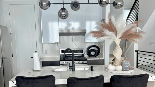 A modern kitchen with white cabinets, a central island with three black bar stools, and pendant lights above the island. - LuxeStay Townhome 5min from Downtown Dallas (Dallas)