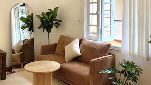 A living room with a brown sofa, a round wooden coffee table, and a large potted plant. - 2 Bedrooms in a Cozy and Aesthetic Villa / Naturally Cool / West Lake / Kotton 2 (Hà Nội)