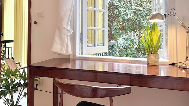 A wooden desk with a chair, a window with curtains, a potted plant, and a wall-mounted lamp. - 2 Bedrooms in a Cozy and Aesthetic Villa / Naturally Cool / West Lake / Kotton 2 (Hà Nội)