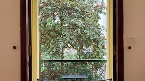 A balcony with two chairs and a table, a potted plant, and a view of a tree and building. - 2 Bedrooms in a Cozy and Aesthetic Villa / Naturally Cool / West Lake / Kotton 2 (Hà Nội)