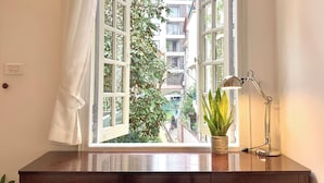 A room with a wooden desk, a potted plant, a desk lamp, and a view through an open window with curtains. - 2 Bedrooms in a Cozy and Aesthetic Villa / Naturally Cool / West Lake / Kotton 2 (Hà Nội)