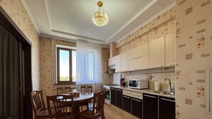 Une cuisine moderne avec des meubles en bois, une table à manger avec des chaises et un lustre.