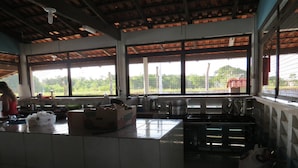A kitchen with tiled walls, a large window, and a counter with various items. - Hotel Agrotur (Manaus)