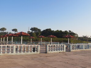 A paved area with a series of red-tiled umbrellas and white balustrades.