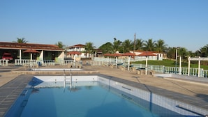 A swimming pool with tiled edges, a metal ladder, and a surrounding area with benches and umbrellas. - Hotel Agrotur (Manaus)