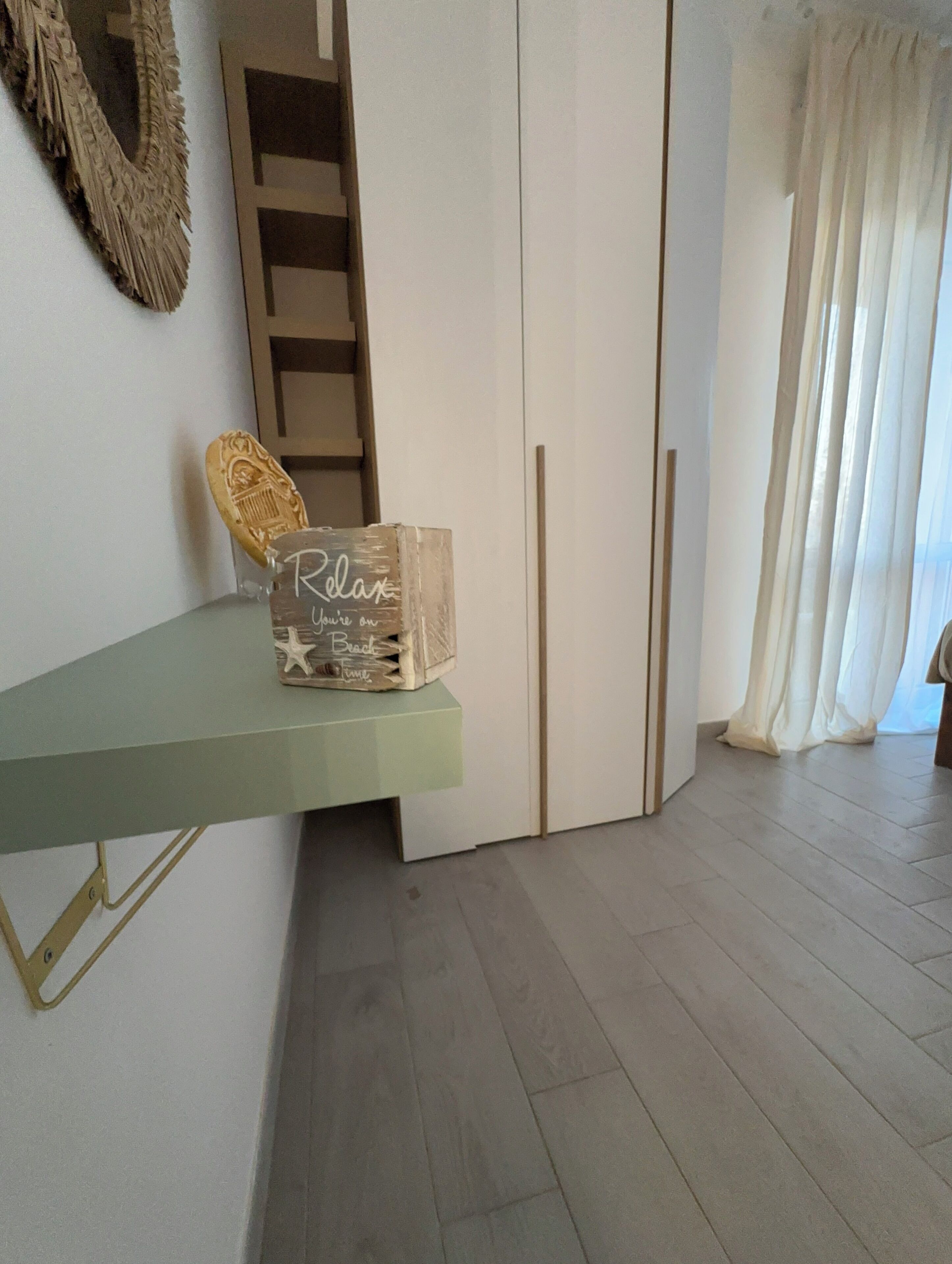 Una habitación con un estante verde que sostiene una caja decorativa y un pequeño adorno con forma de estrella. Se ve un armario blanco al fondo.