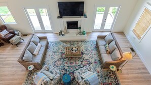 A spacious living room with a large TV, two sofas, a coffee table, and a patterned rug. - Charming 3-beds with loft in peaceful cove on Watts Bar Lake! Bring your boat! (Ten Mile)
