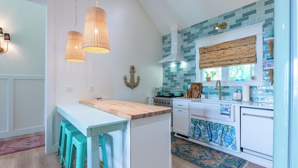 A kitchen with a wooden island, white cabinets, a blue backsplash, and a patterned rug. - Charming 3-beds with loft in peaceful cove on Watts Bar Lake! Bring your boat! (Ten Mile)