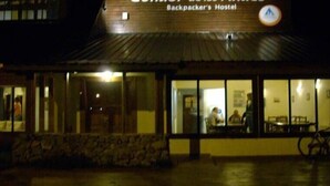 A building labeled "Backpacker Hostel" with large windows and a stone facade. - Condor de los Andes (El Chalten)