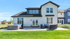 A two-story house with a patio area, large windows, and a covered outdoor seating space.