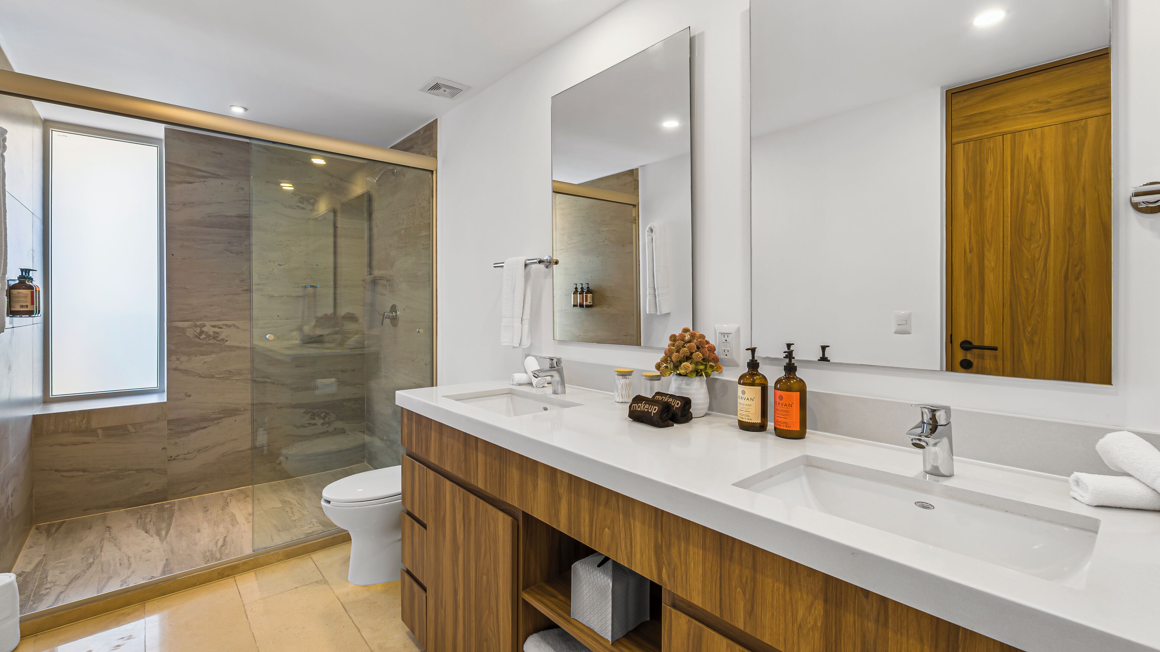 A modern bathroom with a shower, toilet, vanity, and a large mirror.