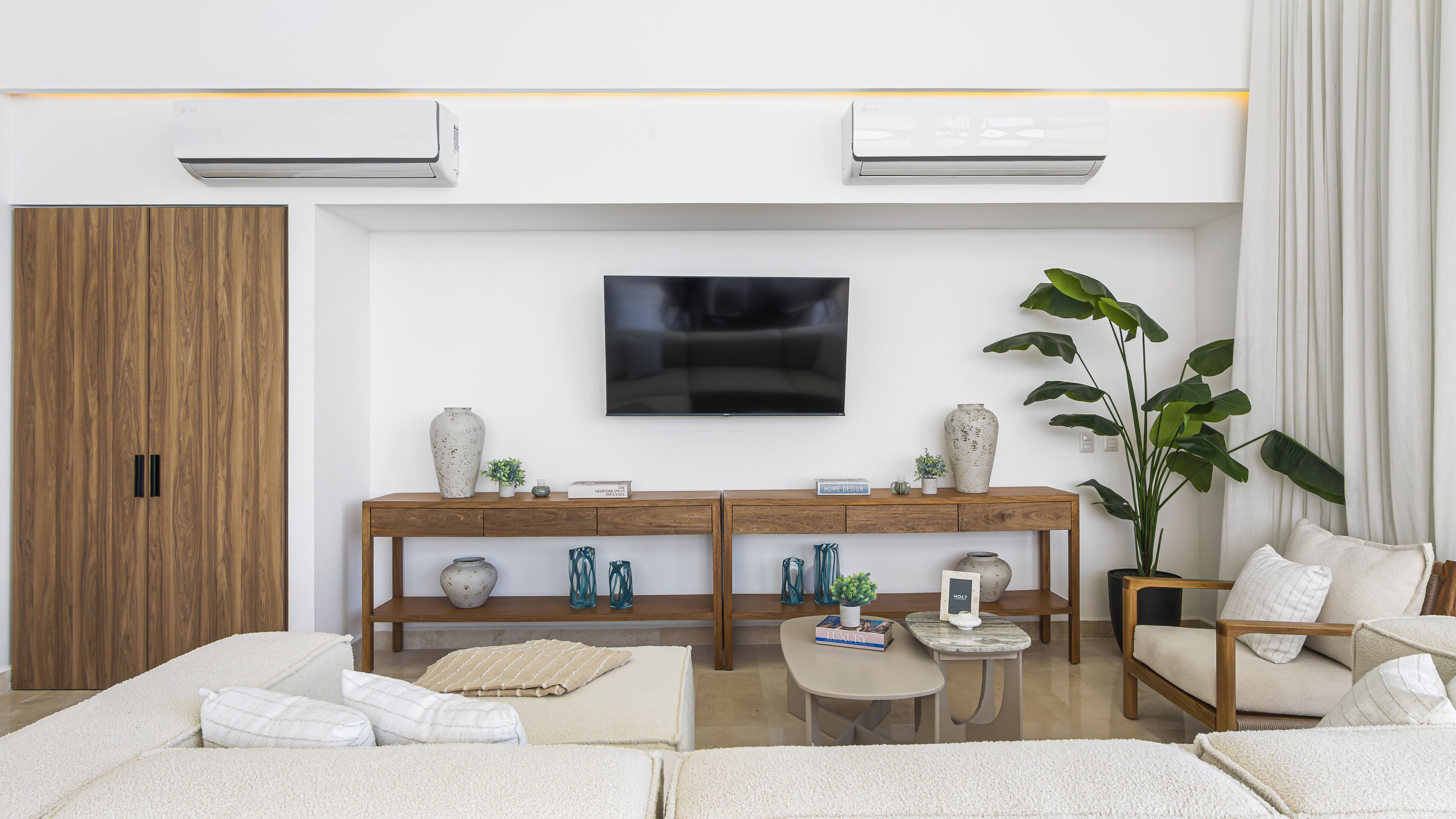 A modern living room with a sofa set, a coffee table, a TV, and a console table with decorative items.