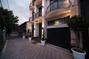 A hotel entrance with a brick-paved driveway, potted plants, and a closed garage door. - Emmanuel Hotel Yerevan (Yerevan)