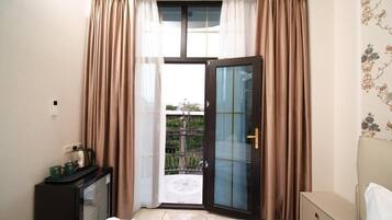 Camera d'albergo con un letto, una scrivania con un bollitore, una porta in vetro e vista all'esterno.