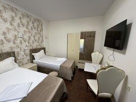 Een hotelkamer met twee bedden, een bureau, een stoel, een televisie en een kledingkast.