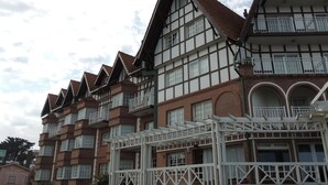 A row of multi-story buildings with a traditional architectural style, featuring prominent gabled roofs and white-framed windows. - Gemelos Apart (Villa Gesell)
