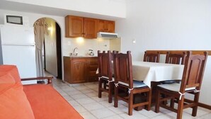 A compact kitchen with wooden cabinets and a dining table with chairs. - Gemelos Apart (Villa Gesell)