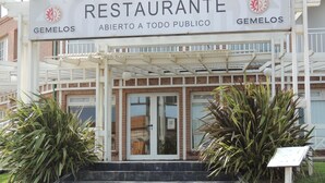 A restaurant entrance with a sign reading "RESTAURANTE ABIERTO A TODO PUBLICO" and "GEMEOS". - Gemelos Apart (Villa Gesell)
