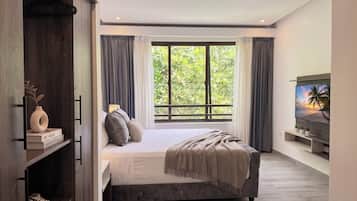 A modern bedroom with a large bed, a wardrobe, a TV, and a window with curtains.