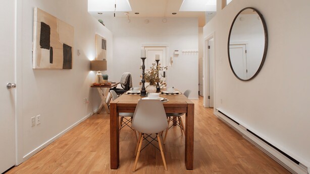 A dining area with a wooden table, white chairs, and a large mirror on the wall. - Spacious 2-Bedroom Condo in Downtown Victoria (Victoria)