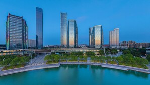A modern cityscape with high-rise buildings, a waterfront promenade, and a bridge. - Days Hotel By Wyndham Suzhou Dushu Lake (Suzhou)