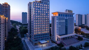 A high-rise hotel with multiple floors, a modern architectural design, and a well-lit entrance area. - Days Hotel By Wyndham Weihai Huoju Eight Street (Weihai)