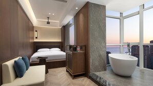 A modern hotel room with a large bed, a sitting area, a bathtub, and a city view. - Days Hotel By Wyndham Weihai Huoju Eight Street (Weihai)