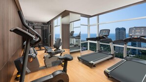 A gym with treadmills, exercise bikes, and weights, featuring large windows with a city view. - Days Hotel By Wyndham Weihai Huoju Eight Street (Weihai)