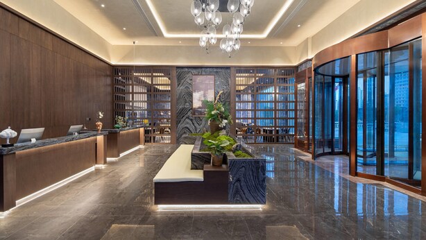 A modern hotel lobby with a reception desk, seating area, and large windows offering city views. - Days Hotel By Wyndham Weihai Huoju Eight Street (Weihai)