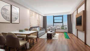 Ein modernes Wohnzimmer mit Essbereich, einer Couch, einem Fernseher und Blick auf die Stadt.