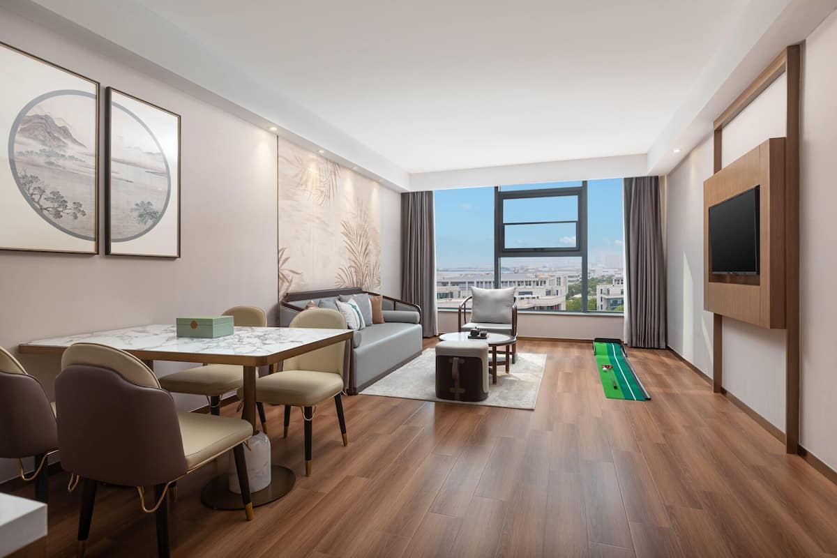 A modern living room with a dining area, a sofa, a TV, and a view of the city.