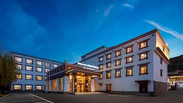 A hotel with a large parking lot, multiple floors, and a well-lit entrance.