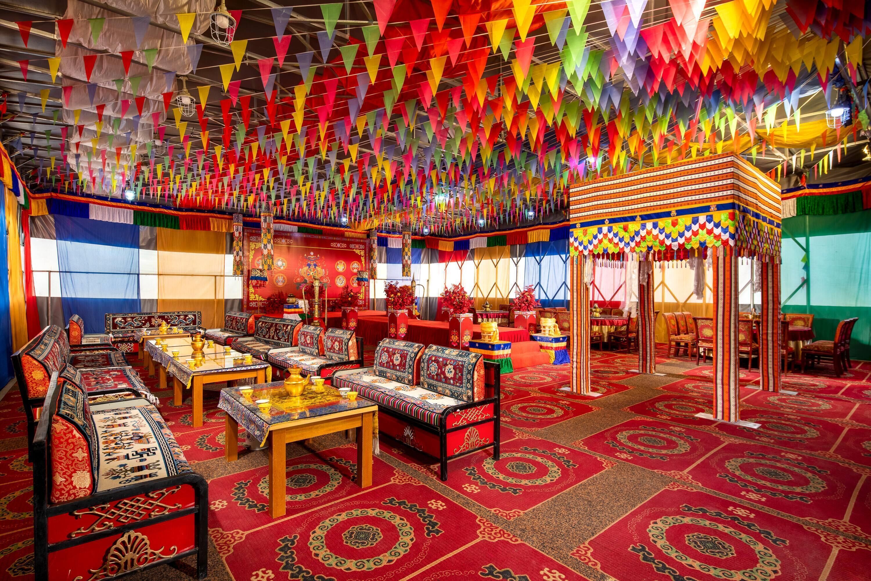 A traditional room with patterned carpets, wooden furniture, and a colorful hanging decoration.