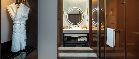 Une salle de bain moderne avec un grand miroir, un peignoir suspendu à un porte-peignoir et un porte-serviettes.