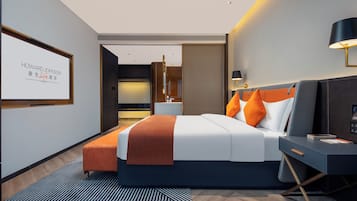 Una habitación de hotel moderna con una cama grande, un escritorio y un televisor mostrando 'HOWARD JOHNSON'.