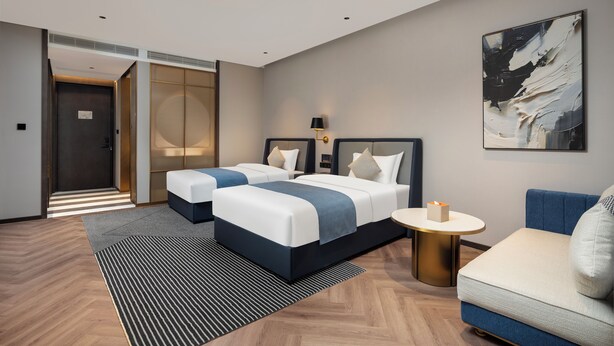 A hotel room with two beds, a sofa, a round table, and a painting on the wall. - Howard Johnson Life Qingyang Chengdu (Chengdu)
