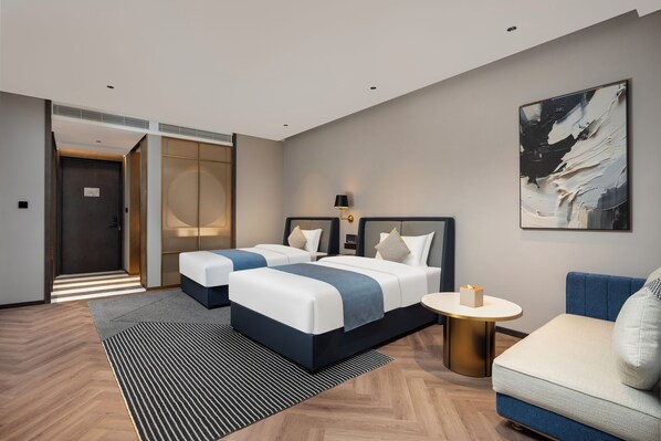 A hotel room with two beds, a sofa, a round table, and a painting on the wall. - Howard Johnson Life Qingyang Chengdu (Chengdu)