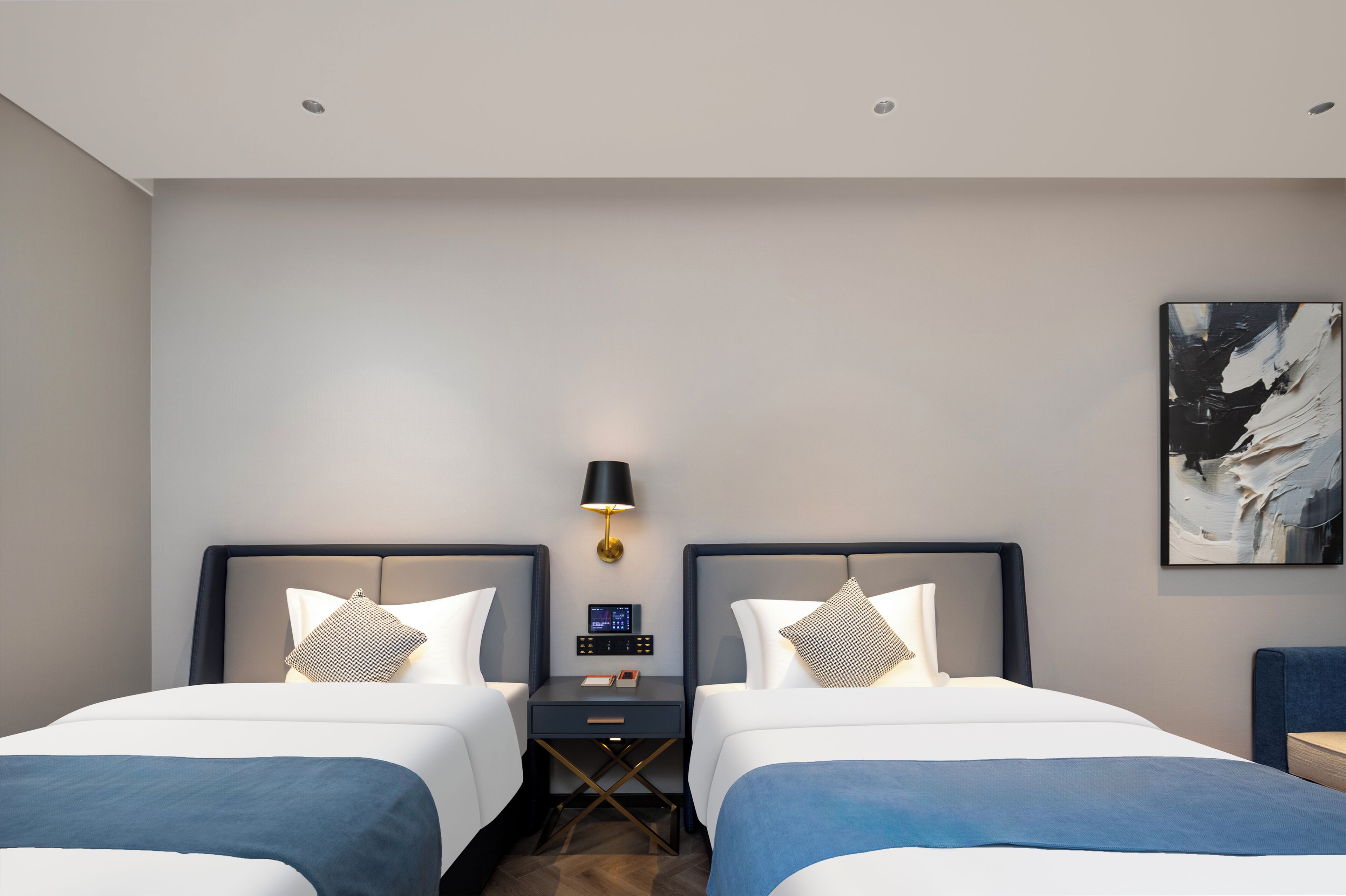 A hotel room with two beds, a bedside table with a lamp, a digital control panel, and a painting on the wall.