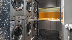 A commercial laundry area with multiple washing machines, a control panel, and a sink. - Howard Johnson Life Qingyang Chengdu (Chengdu)