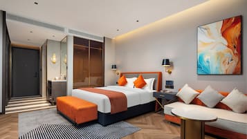 Una camera d'albergo moderna con un letto grande, un divano, un tavolino da caffè e un quadro appeso al muro.
