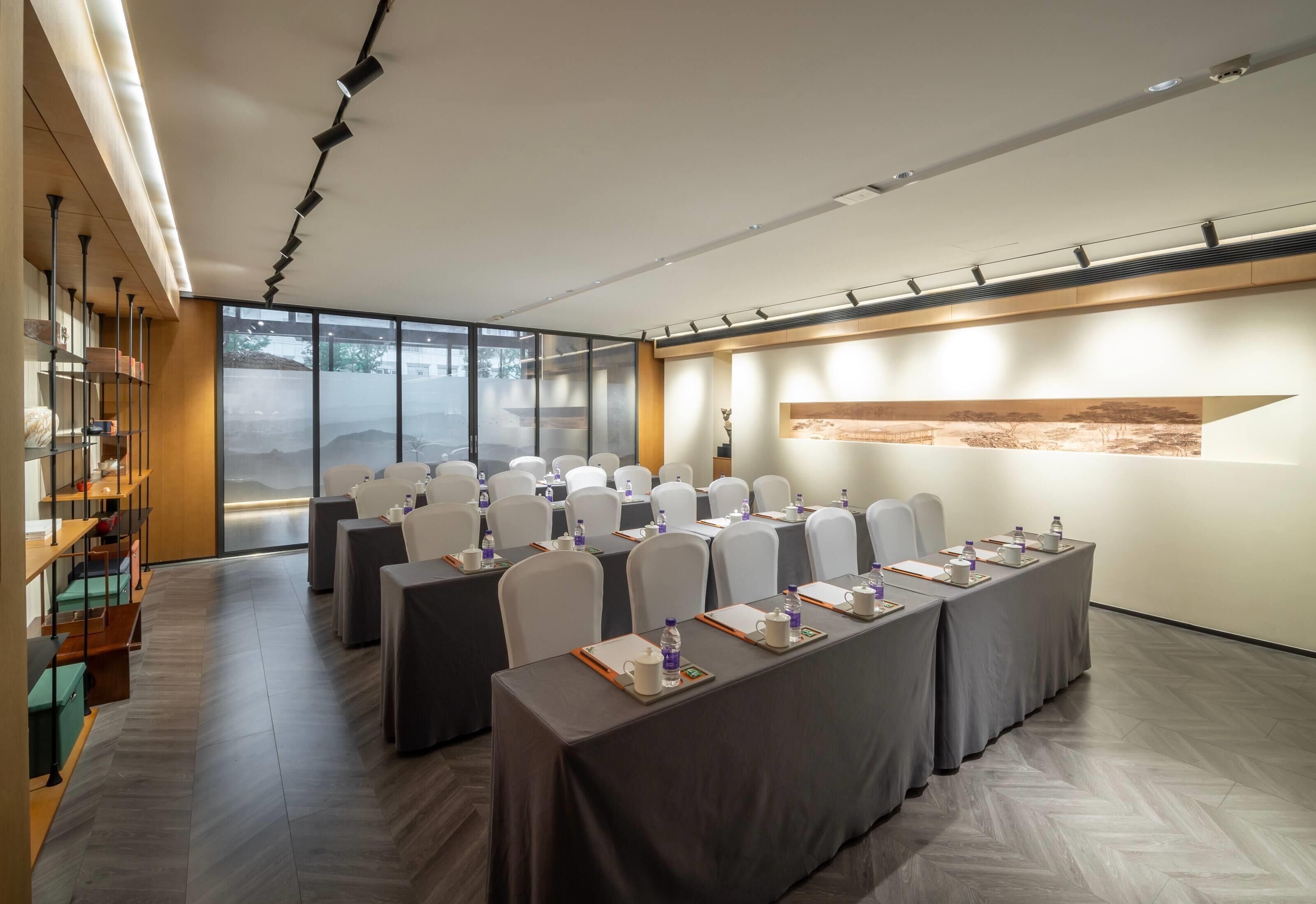A conference room with long tables, chairs, and a large window.