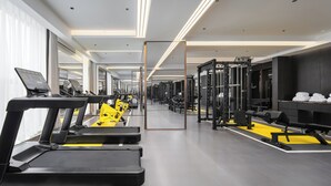Ein modernes Fitnessstudio mit Laufbändern, Kraftgeräten und einer Spiegelwand.