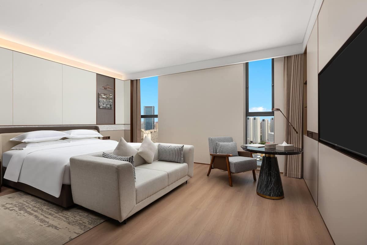 Une chambre d’hôtel moderne équipée d’un lit, d’un canapé, d’une petite table et d’un téléviseur.