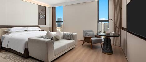 Ein modernes Hotelzimmer mit Bett, einer Couch, einem kleinen Tisch und einem Fernseher.