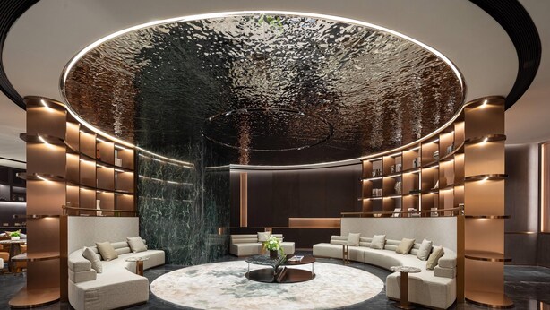 Eine moderne Lobby mit einer runden Sitzecke, Marmorböden und einer großen, spiegelnden Decke.