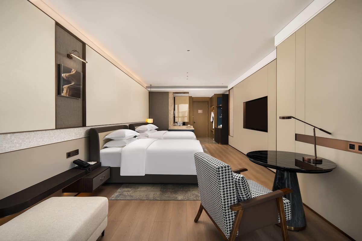 Une chambre d’hôtel moderne équipée d’un grand lit, d’un bureau, d’une chaise et d’un téléviseur.