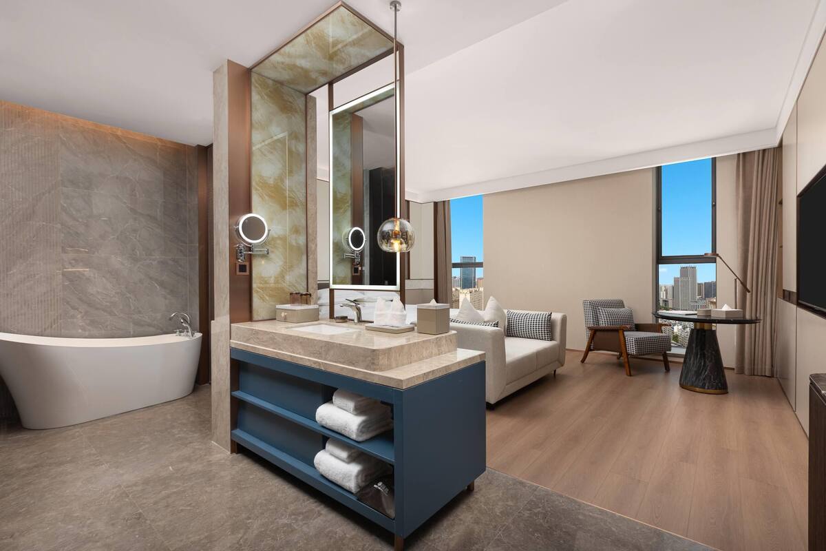 Une salle de bain moderne avec une baignoire sur pieds, un grand miroir et un meuble-lavabo doté d’un plan de travail en marbre.