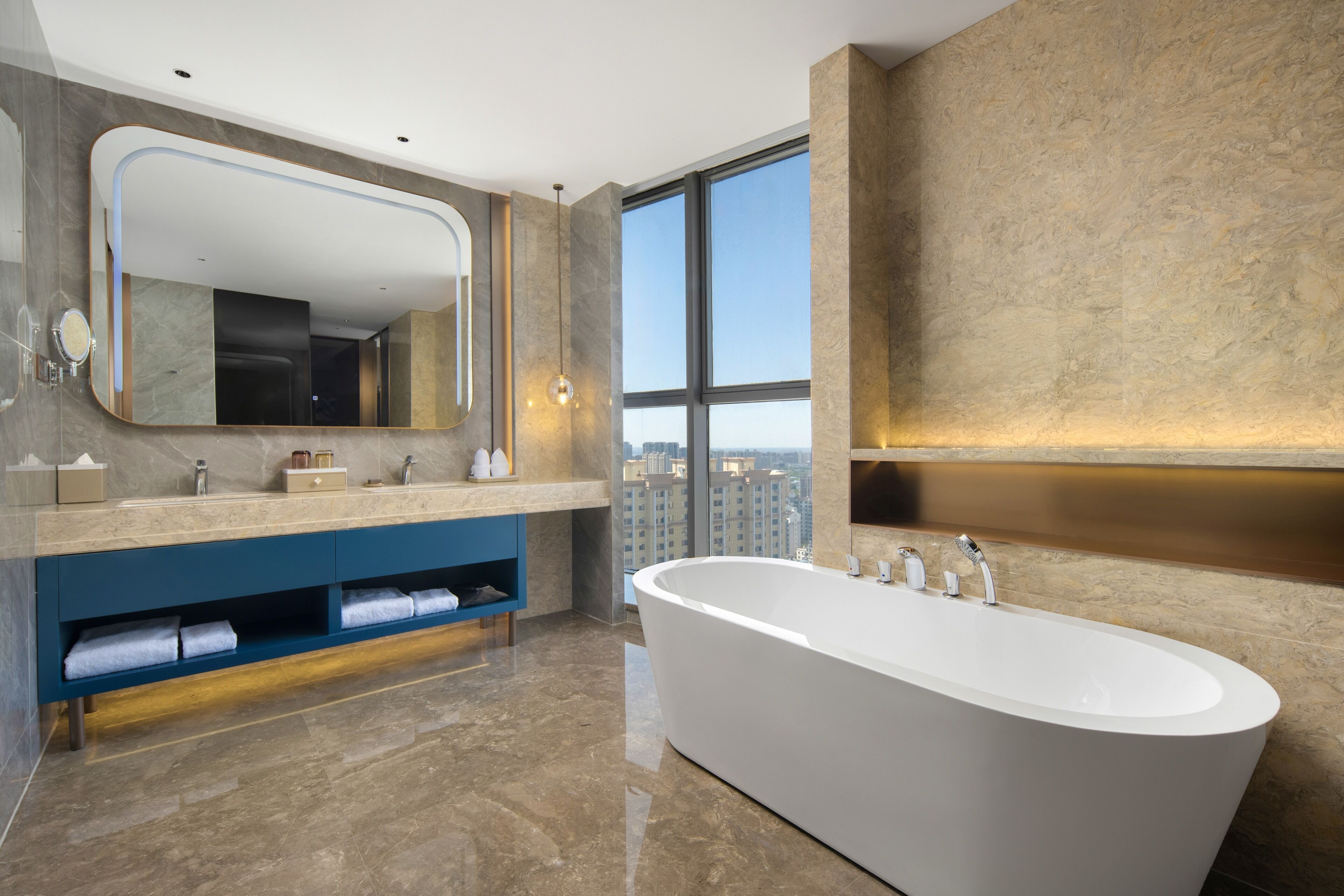 Un baño moderno con una bañera independiente, un espejo grande y un tocador con lavamanos integrado.
