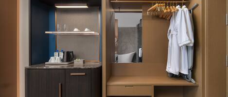 A modern bathroom with a dark wood vanity, a mirror, and a wooden robe rack.