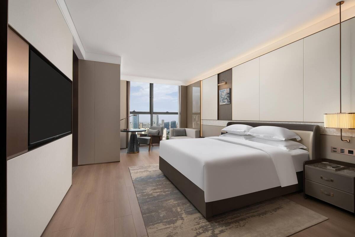 Une chambre d’hôtel moderne avec un grand lit, un bureau et une vue sur la ville.